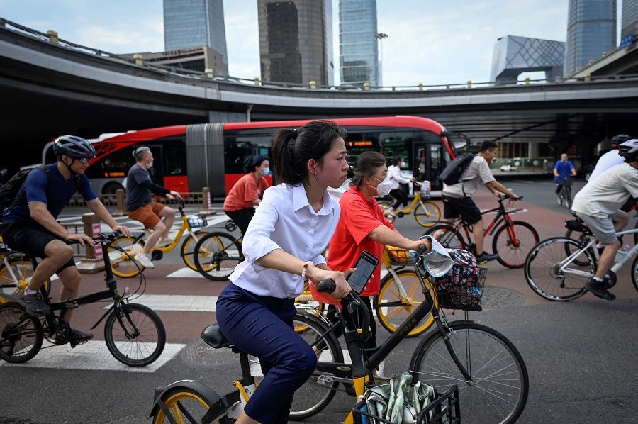 Commuters ride bicycles along a street in the central business district in Beijing, China, on 8 July 2022. (Wang Zhao/AFP)