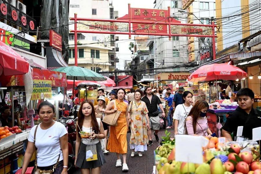 This photo taken on 4 July 2023 shows tourists walking along a street in the Chinatown area of Bangkok. (Sai Aung Main/AFP)