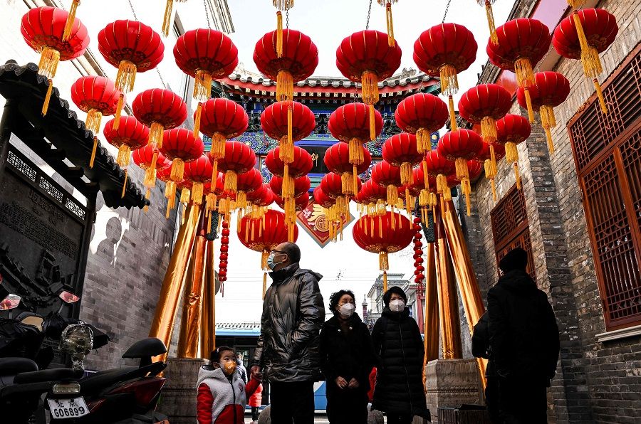 People walk under lanterns along an alley in Beijing, China, on 21 January 2023. (Noel Celis/AFP)
