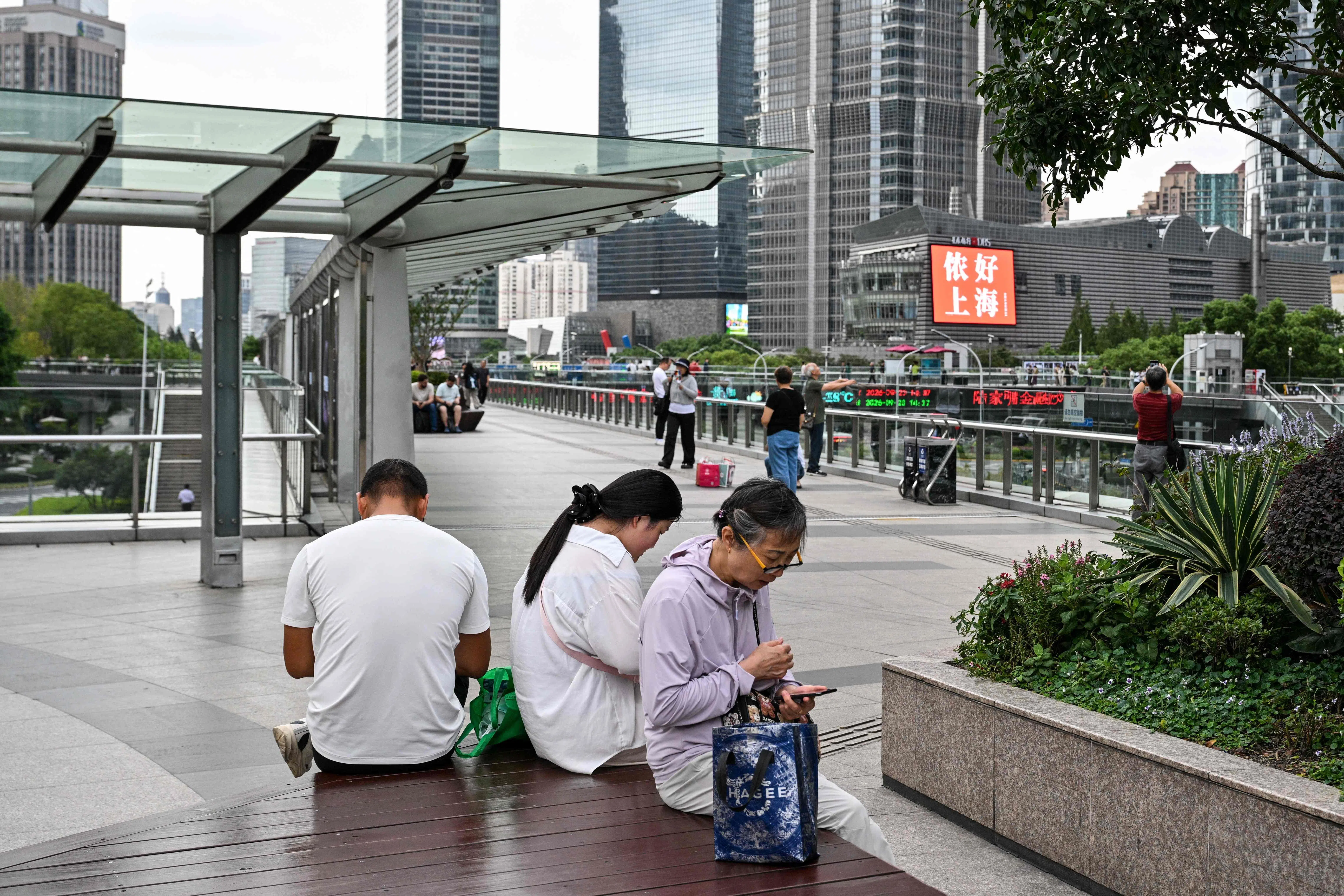 People look at their smartphones in the financial district of Shanghai on 23 September 2026.