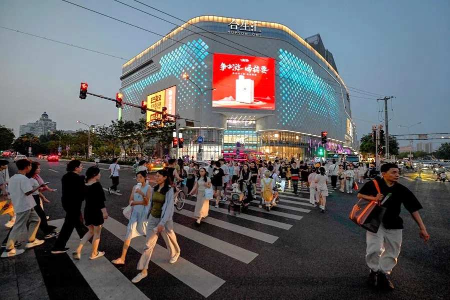 People cross a road outside a shopping mall in Beijing, China, on 1 July 2025. (Adek Berry/AFP)
