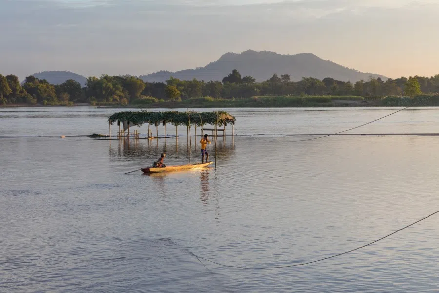 Two men working at a power line to connect a partially submerged shelter in Si Phan Don near Don Puay, Laos, December 2017.