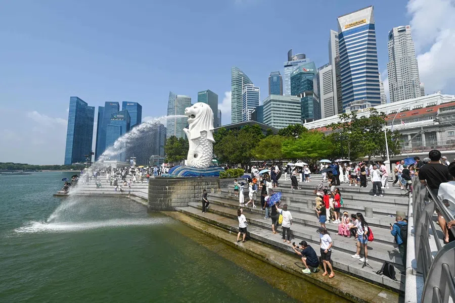 People take pictures next to the Merlion statue at the Marina Bay waterfront in Singapore on 30 July 2025. (Roslan Rahman/AFP)