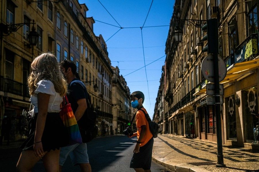 Tourists cross a street in downtown Lisbon on 14 July 2021. (Patricia de Melo Moreira/AFP)