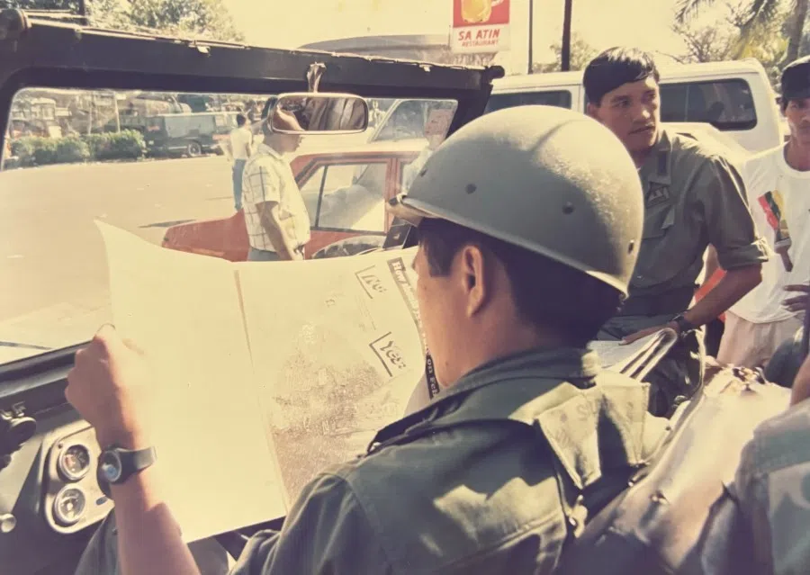 Government troops read the news of the day while surrounding rebel soldiers.