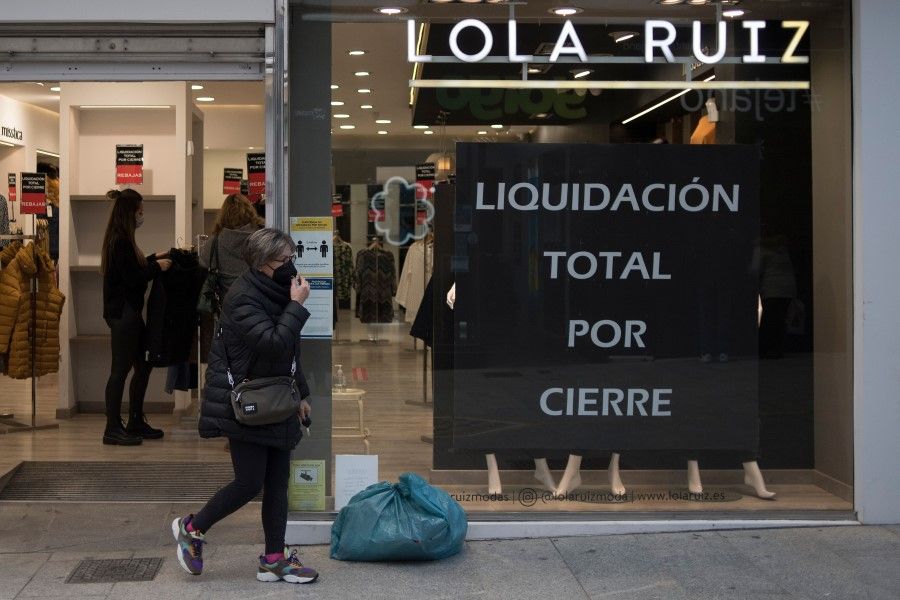 A woman walks past a store with a sign announcing a clearance sale in central Ronda on 22 January 2021 as new coronavirus measures came into force in the Andalusia region. Soaring coronavirus infection rates are heaping pressure on Spain's hospitals and intensifying a power struggle between regional and central government, in one of Europe's hardest-hit countries. (Jorge Guerrero/AFP)