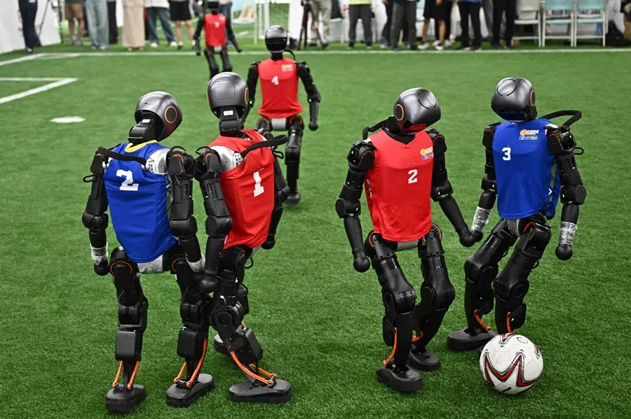 Humanoid robots vie for the ball during an exhibition football match ahead of the World Humanoid Robot Games in Beijing on 4 August 2025. (Pedro Pardo/AFP)