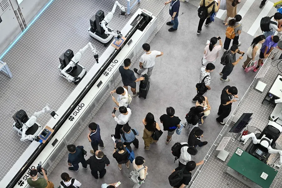 People walk next to robots during the World Artificial Intelligence Conference (WAIC) in Shanghai on 18 July 2026.