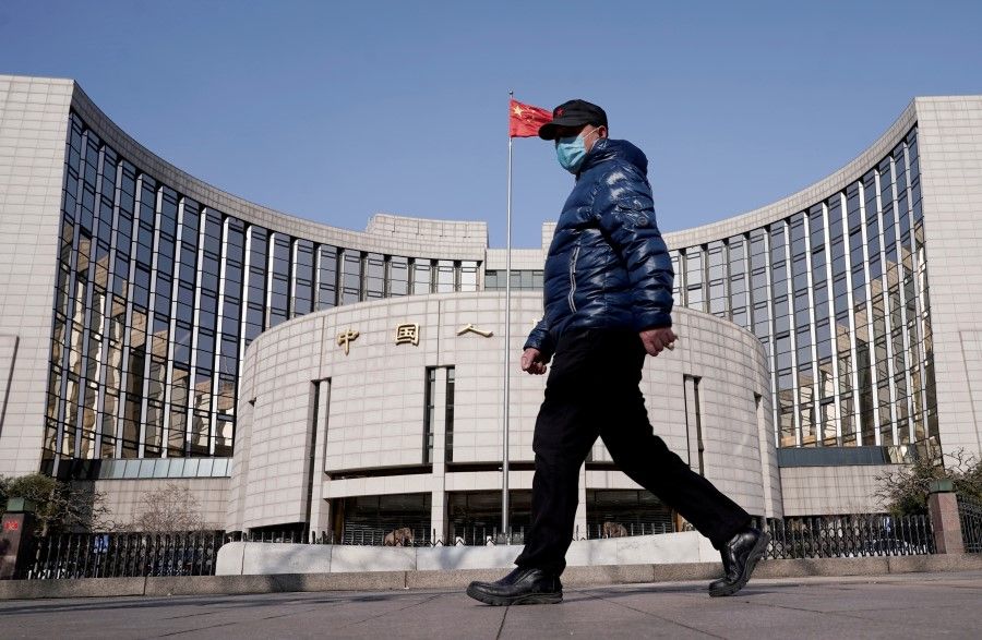 A man wearing a mask walks past the headquarters of the People's Bank of China, the central bank, in Beijing, China, February 3, 2020. (Jason Lee/Reuters)