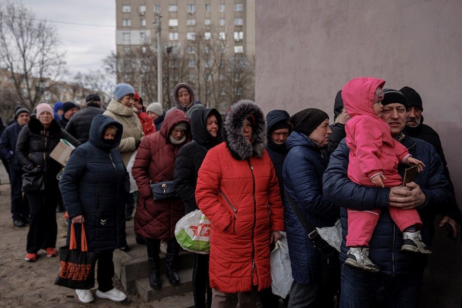 People line up for food handed out by volunteers at a humanitarian aid distribution point, as Russia's attack on Ukraine continues, in Kharkiv, Ukraine, 28 March 2022. (Thomas Peter/Reuters)