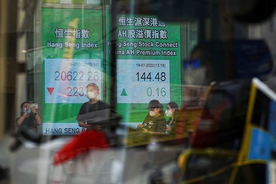 A vehicle drives past a screen displaying the Hang Seng Index at Central district, in Hong Kong, China, 19 July 2022. (Lam Yik/Reuters)