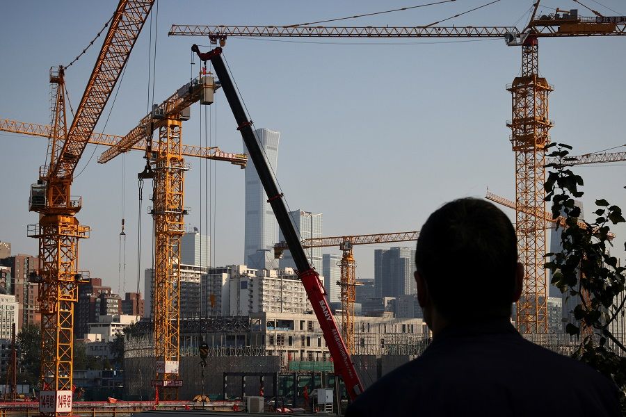 A person looks towards cranes in front of the skyline of the central business district (CBD) in Beijing, China, 18 October 2021. (Thomas Peter/Reuters)