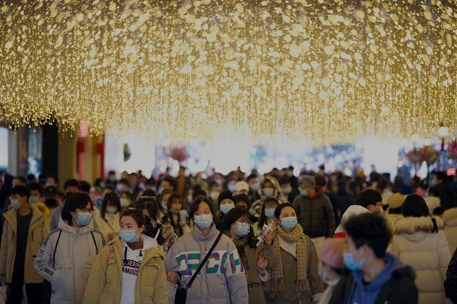 People wearing face masks walk along a shopping centre in Wuhan, Hubei province, China, on 1 January 2021. (Noel Celis/AFP)
