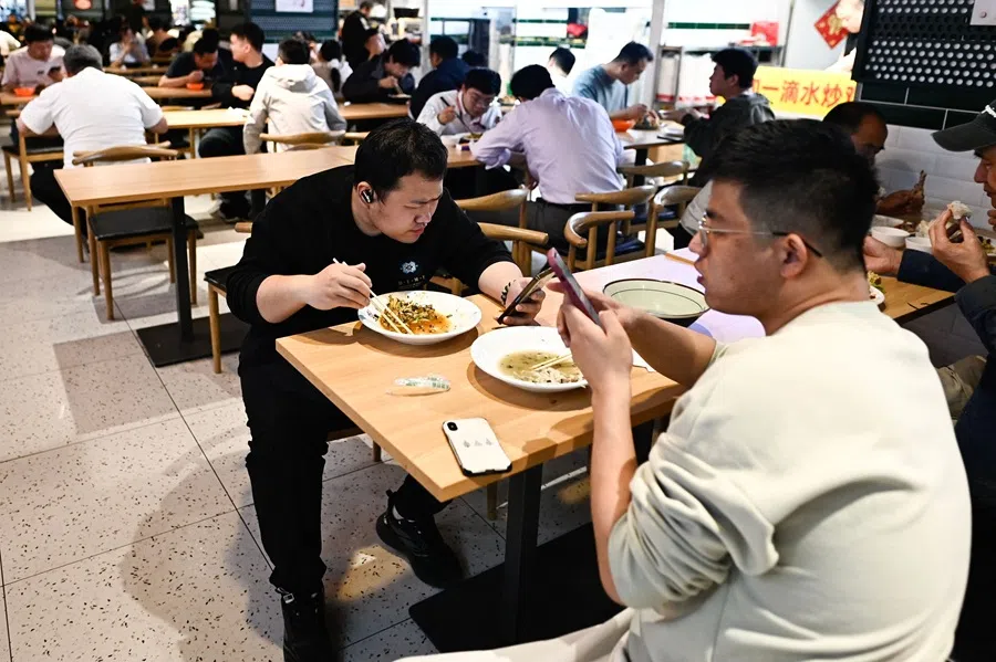 People eat during their lunch break in Beijing, China, on 28 April 2025. (Pedro Pardo/AFP)