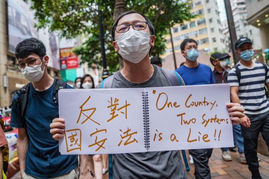 A demonstrator holds a sign reading "One Country, Two Systems is a Lie" as he marches through the Causeway Bay district during a protest in Hong Kong, 27 May 2020. (Lam Yik/Bloomberg)