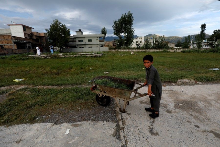 A boy stands with a wheelbarrow at the demolished former compound of Osama bin Laden in Abbottabad, Pakistan, 10 September 2021. (Akhtar Soomro/Reuters)