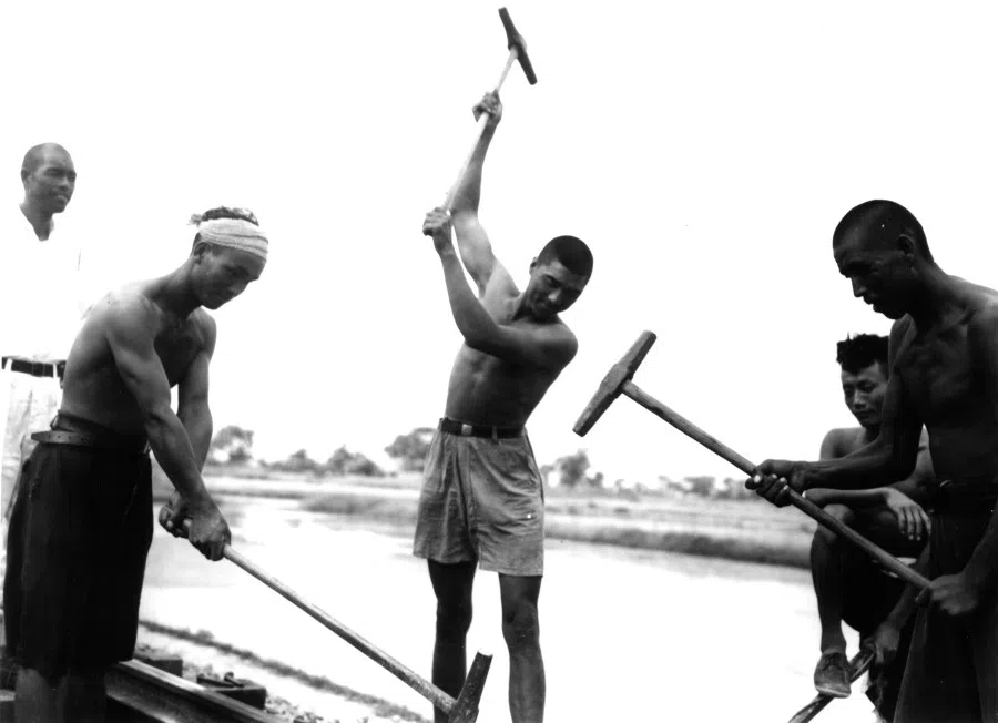 Workers hammer a railway in place.