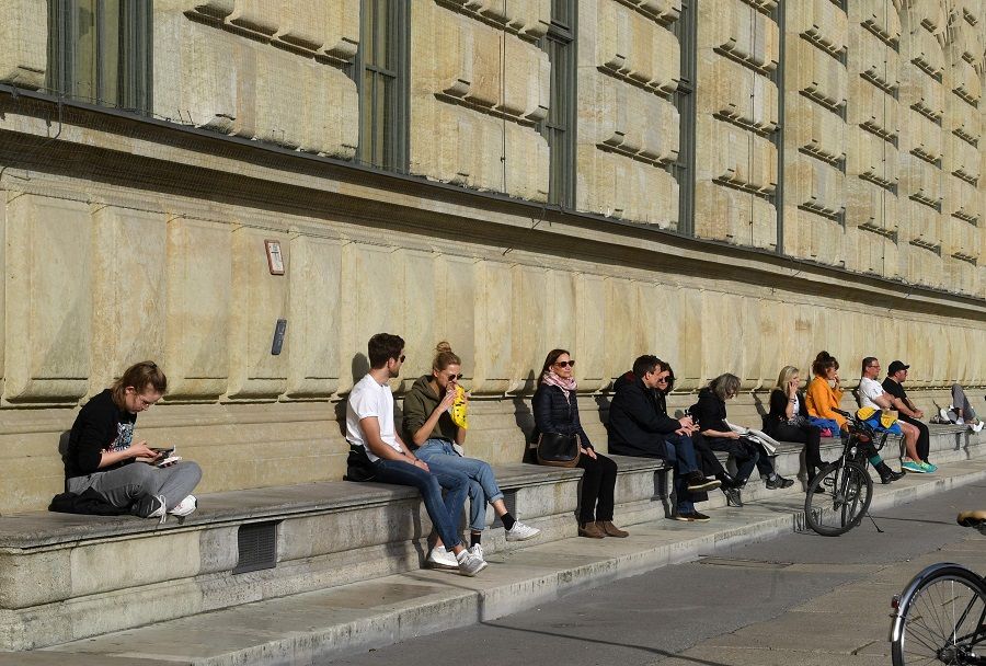 People enjoy the sunny warm weather in front of the residence at the Max-Joseph-Platz in the city of Munich, Germany, on 27 March 2020. (Christof Stache/AFP)