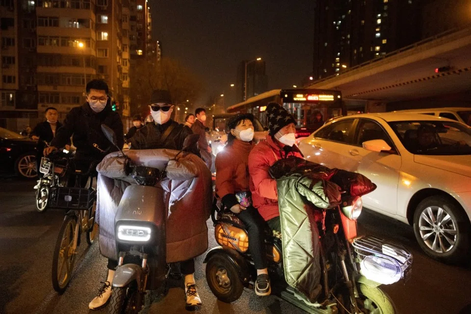 People on scooters wait in evening rush-hour traffic in the central business district on a day with heavy pollution in Beijing, China, 10 March 2023. (Thomas Peter/Reuters)