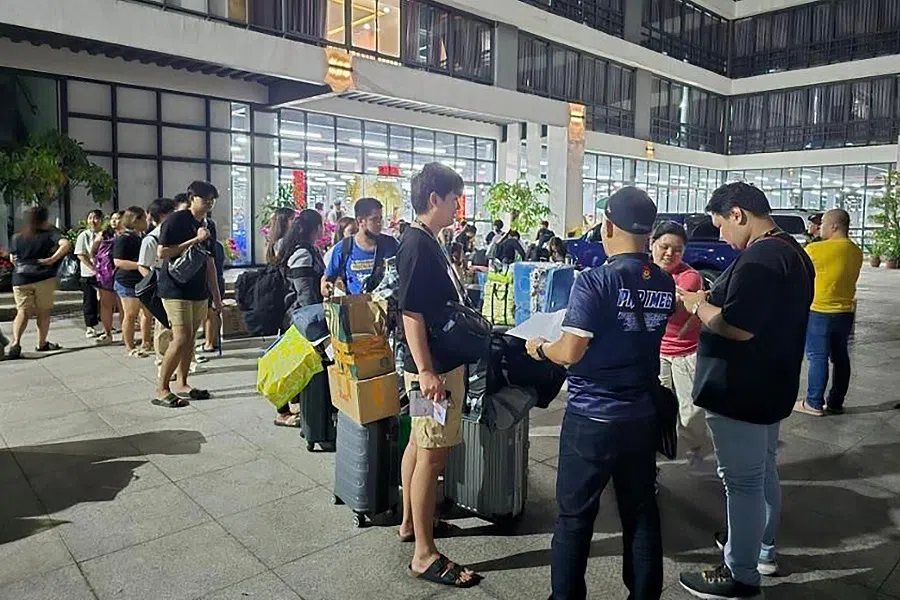 This undated handout photograph received from Philippines’ Presidential Anti-Organized Crime Commission (PAOCC) on 14 March 2024 shows a police officer (front, center) talking to foreign nationals after a raid in a 10-hectare (25-acre) complex of buildings in Bamban town of Tarlac province, north of Manila. (Philippines’ Presidential Anti-Organized Crime Commission (PAOCC)/AFP)