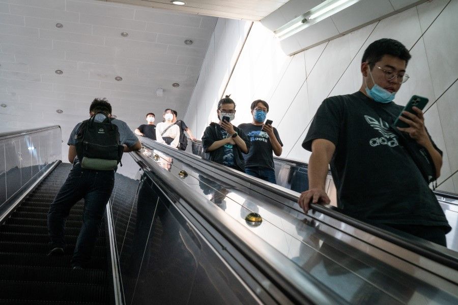 Visitors use their smartphones as they ride on an escalator in Beijing, China on 16 July 2021. China's regulatory crackdown on technology companies shows how technology is quickly turning into the next major battleground in a clash of superpowers, with implications that potentially could reshape the global economy for decades to come. (Yan Cong/Bloomberg)