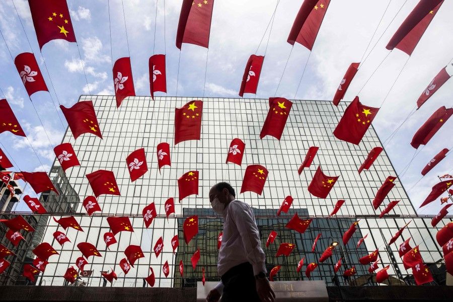 A man walks under a display of the Hong Kong and Chinese flags in the Tsim Sha Tsui district of Hong Kong on 29 September 2022, ahead of China's National Day on 1 October. (Isaac Lawrence/AFP)
