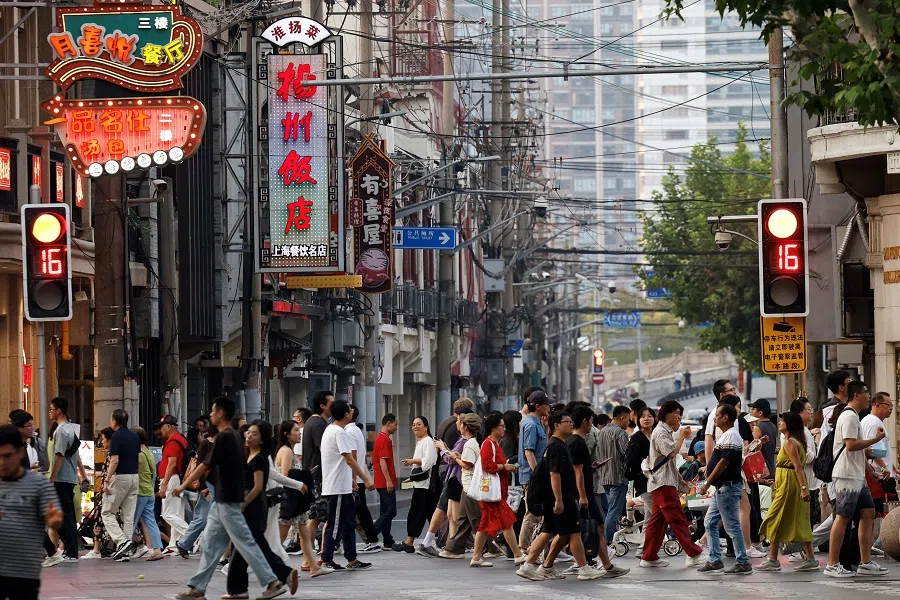 People walk past a lane lined up with restaurants, at a shopping area in Shanghai, China, on 28 September 2024. (Tingshu Wang/Reuters)