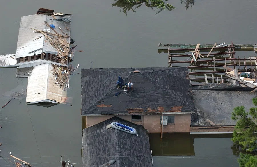 People sit on a roof waiting to be rescued after Hurricane Katrina, in New Orleans, Louisiana, US, 30 August 2005. (Jocelyn Augustino/FEMA; Wikimedia)