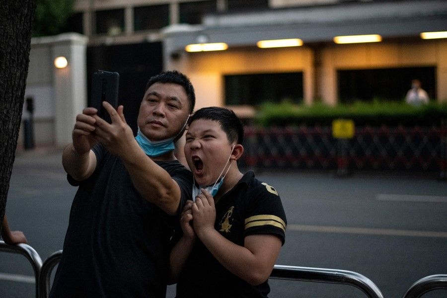 People take selfies in front of the US Consulate in Chengdu, 27 July 2020. (Noel Celis/AFP)