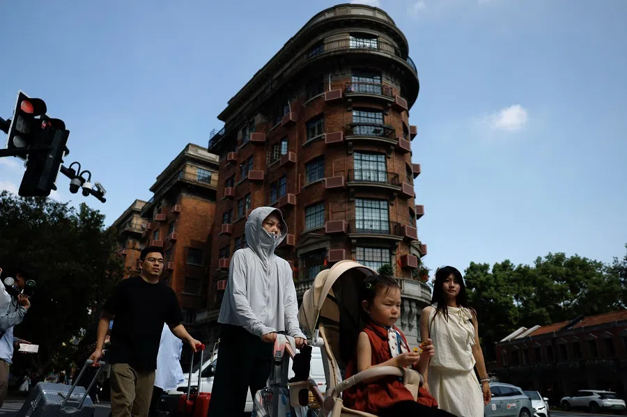 A woman pushes a child in a trolley in Shanghai, China, on 28 September 2024. (Tingshu Wang/Reuters)