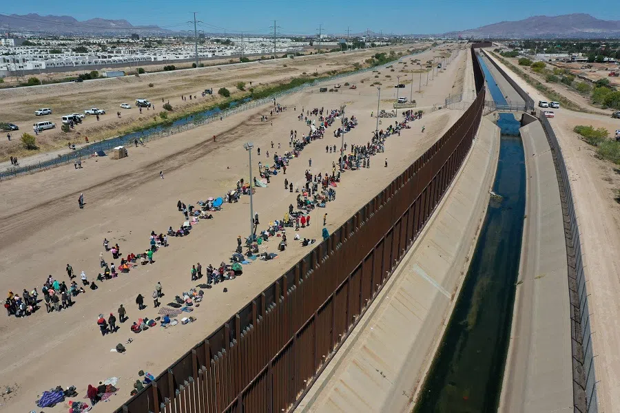An aerial image shows migrants waiting along the border wall to surrender to US Customs and Border Protection (CBP) border patrol agents for immigration and asylum claim processing after crossing the Rio Grande River into the US, on the US-Mexico border in El Paso, Texas, on 11 May 2023. (Patrick T. Fallon/AFP)