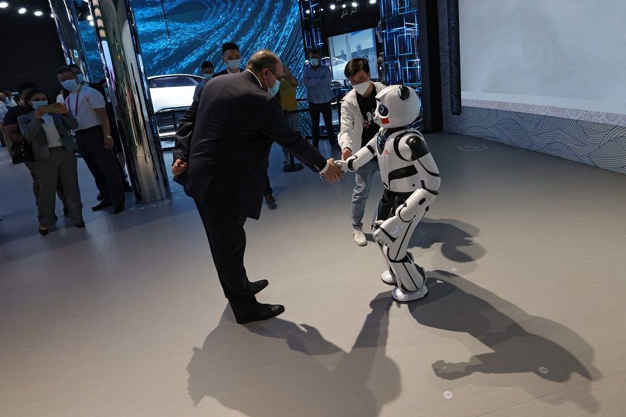 In this file photo taken on 3 October 2021, a man shakes hands with a panda robot at the China Pavilion at the Expo 2020, in the Gulf Emirate of Dubai. (Giuseppe Cacace/AFP)