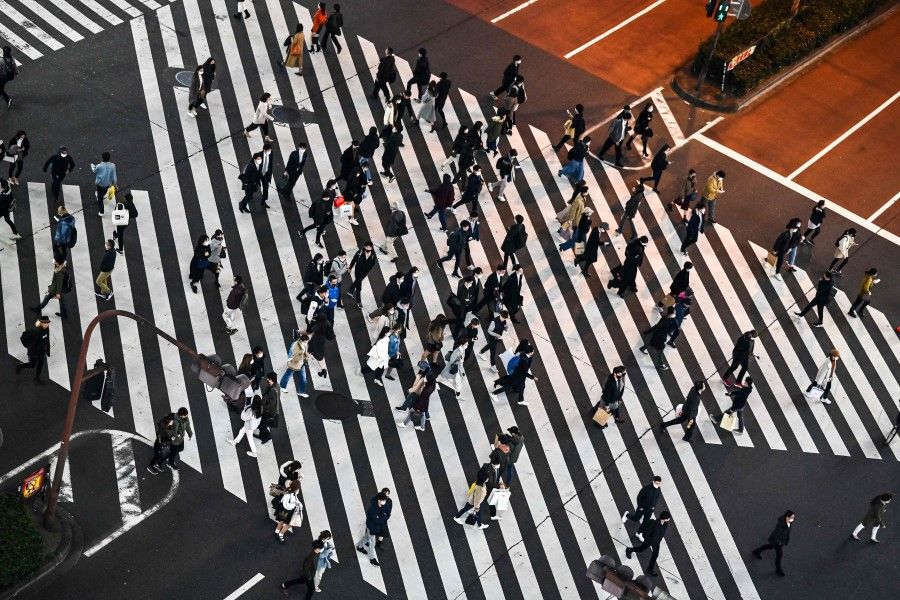 Pedestrians cross a street in Tokyo's Shinjuku area on 29 November 2020, as the city reported 418 new infections of the Covid-19 coronavirus. (Charly Triballeau/AFP)