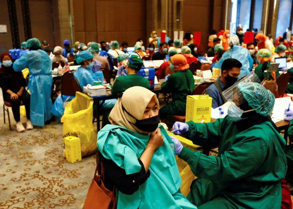 A woman receives her first dose of China's Sinovac Biotech vaccine for the coronavirus disease (Covid-19) during a mass vaccination program for vendors and workers at a shopping mall in Tangerang, on the outskirts of Jakarta, Indonesia, 1 March 2021. (Ajeng Dinar Ulfiana/Reuters)