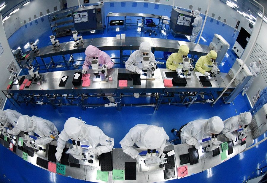 Employees work on a production line manufacturing camera lenses for mobile phones at a factory in Lianyungang, Jiangsu province, China, 30 April 2019. (China Daily via Reuters)