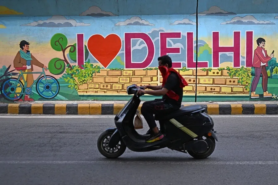 A motorist rides past a mural along a street in New Delhi on 5 August 2026.