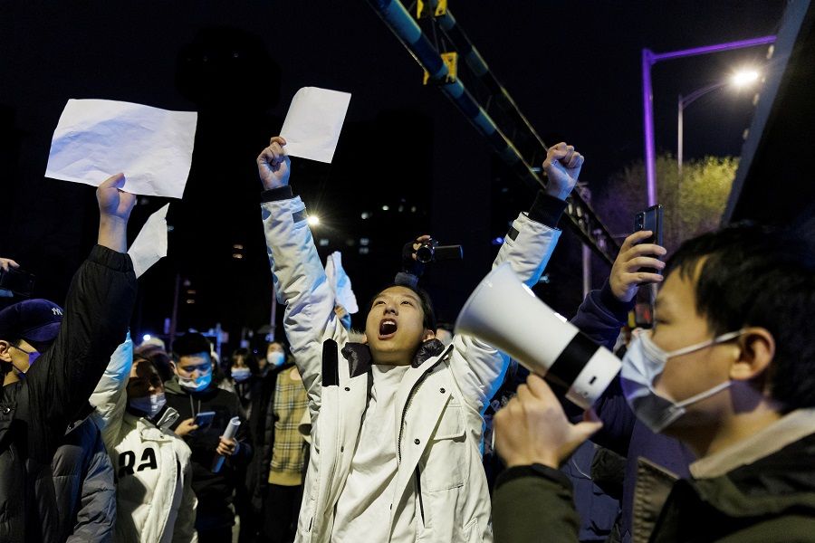 People hold white sheets of paper in protest over Covid-19 restrictions after a vigil for the victims of a fire in Urumqi, as outbreaks of Covid-19 continue, in Beijing, China, 28 November 2022. (Thomas Peter/Reuters)