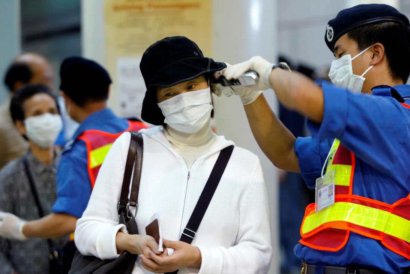 In this file photo, a health worker wearing a mask to protect from SARS takes a woman’s temperature, after the latter arrived in Hong Kong by train from Guangzhou, on 24 April 2003. (Kin Cheung/File Photo/Reuters)