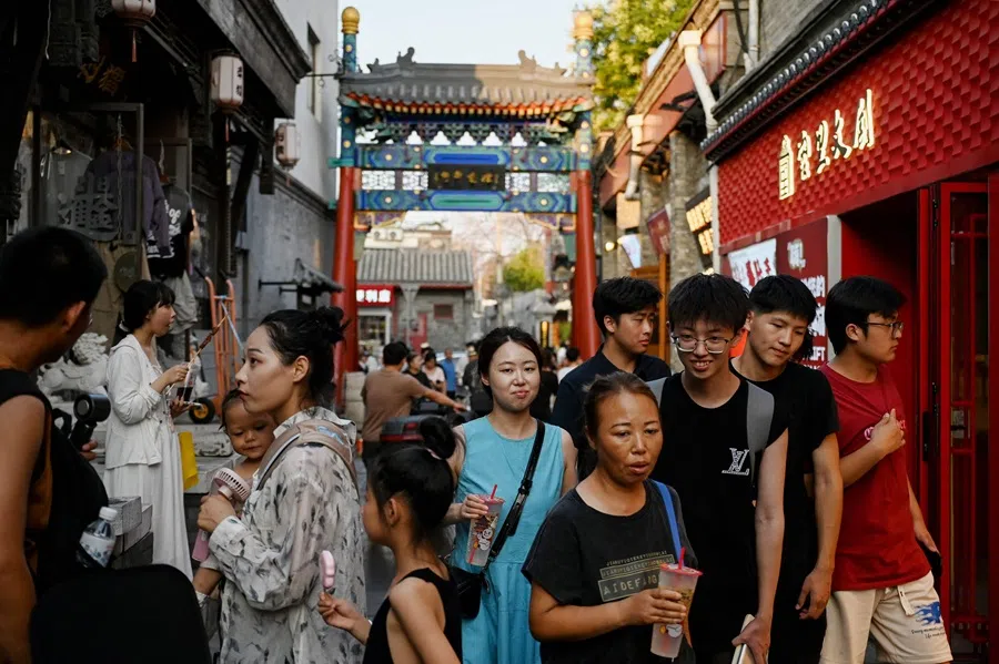 People walk along an alley near the Houhai Lake in Beijing on 22 July 2025.
