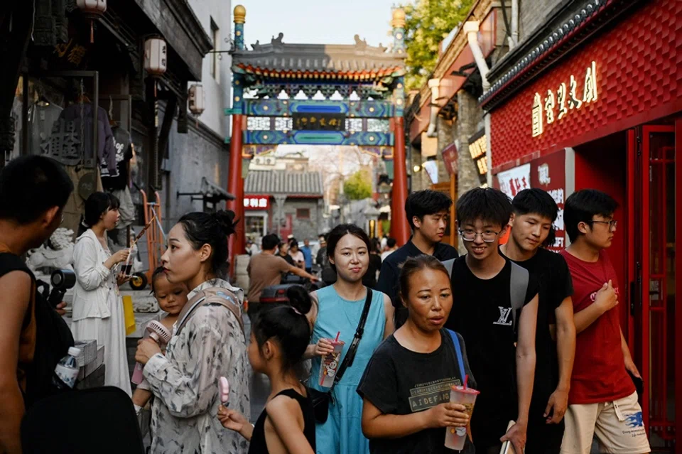People walk along an alley near the Houhai Lake in Beijing on 22 July 2025. (Greg Baker/AFP)