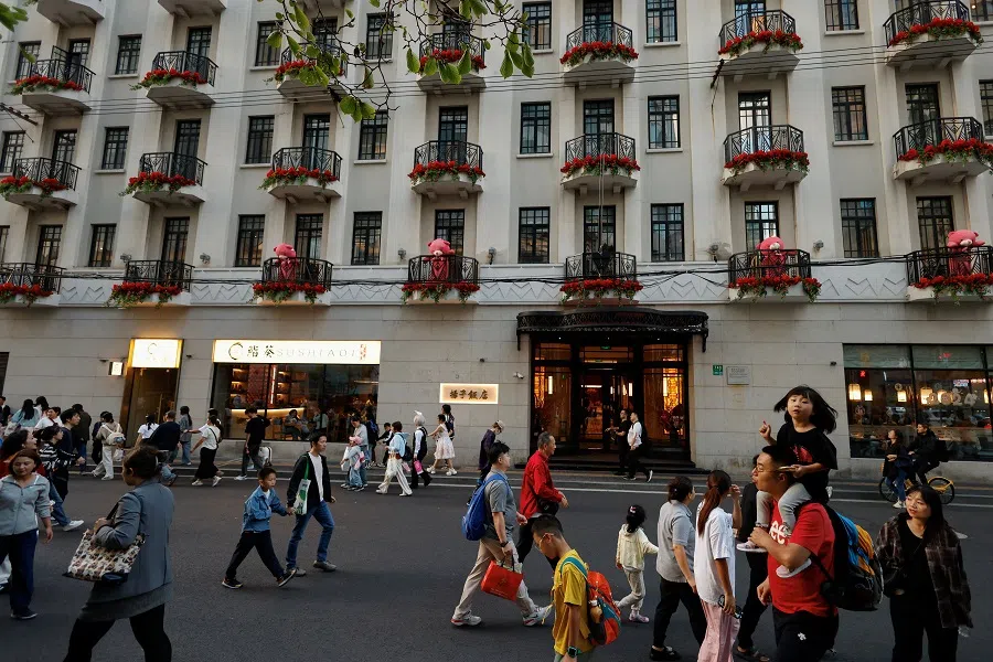 People walk on a street in Shanghai, China, on 3 October 2024. (Tingshu Wang/Reuters)