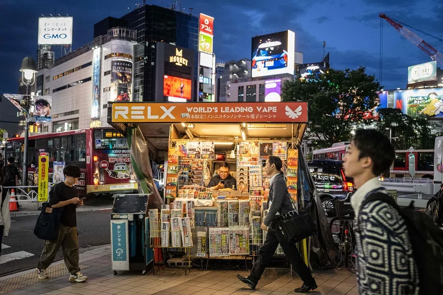 People walk past a newspaper stand in Shibuya area of Tokyo on 4 June 2024.  (Yuichi Yamazaki/AFP)