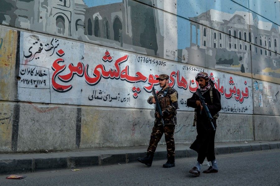 Taliban fighters patrol along a road on the backdrop of a mural painted on the wall of a flyover in Kabul on 26 September 2021. (Hoshang Hashimi/AFP)