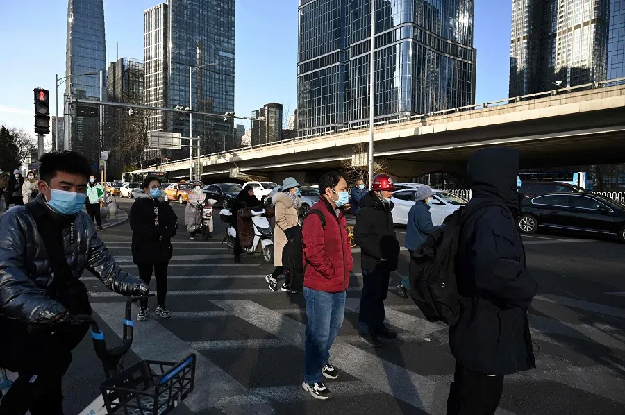 People cross a road in the central business district in Beijing, China, on 16 December 2021. (Greg Baker/AFP)