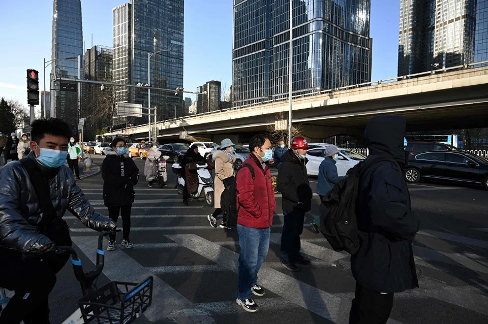 People cross a road in the central business district in Beijing, China, on 16 December 2021. (Greg Baker/AFP)