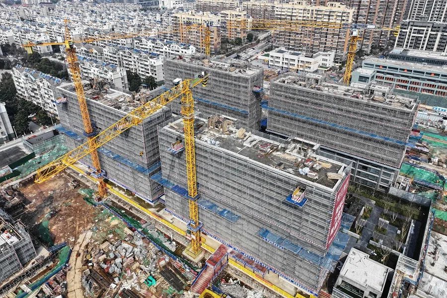 Workers are seen on a rooftop of a residential building under construction in Nanjing, in eastern China's Jiangsu province, on 7 March 2024. (AFP)