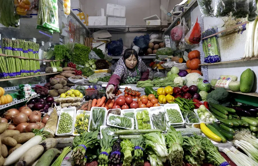 A vendor reaches out for vegetables at her shop in a market in Beijing on 18 February 2016. (Jason Lee/Reuters)