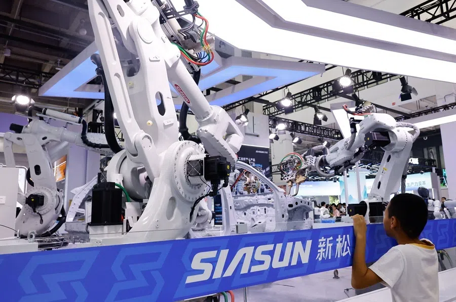 A boy looks at industrial robots installed as a part of a car assembly line at Siasun booth at the 2026 World Robot Conference, in Beijing, China, on 19 August 2026.