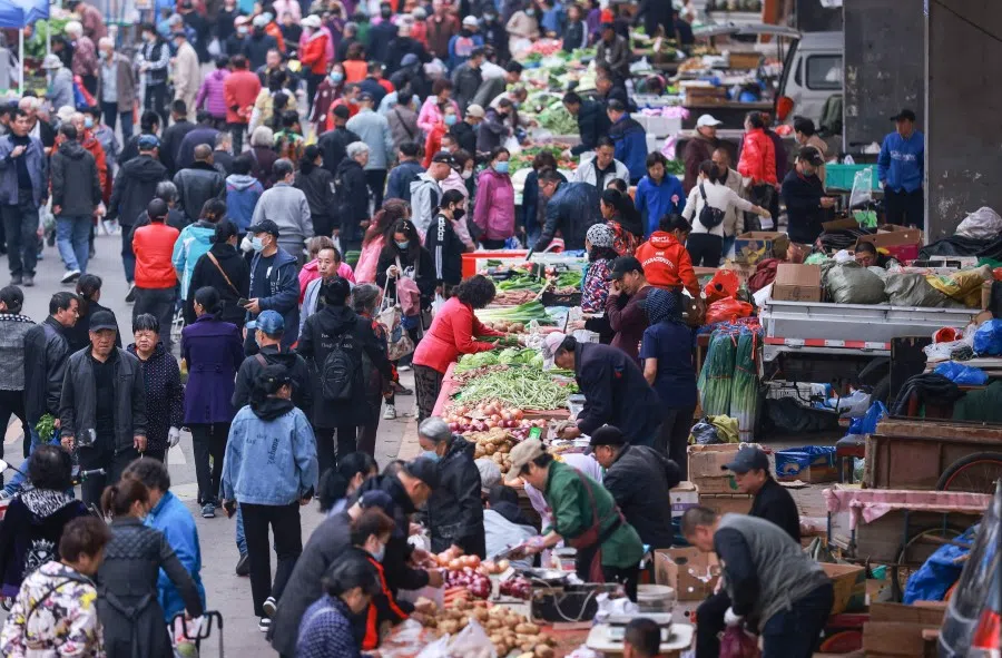 People buy vegetables at a market in Shenyang in China's northeastern Liaoning province on 14 October 2021. (STR/AFP)