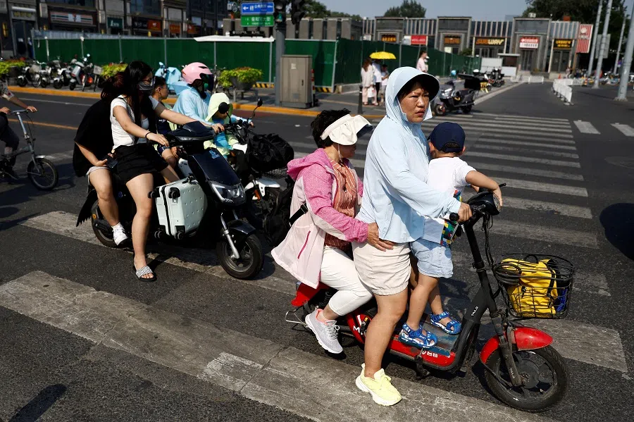 People ride on scooters on a street in Beijing, China, 19 July 2023. (Tingshu Wang/Reuters)